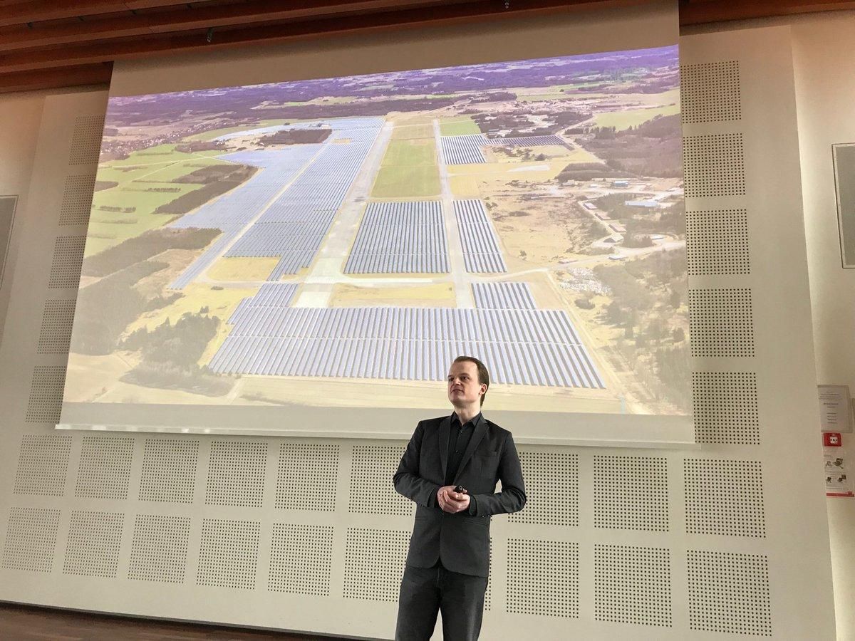 Dale presenting in front of a projected aerial photograph of a large solar park